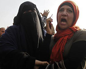 A supporter (L) of Egyptian President Mohamed Mursi confronts Hend Mokhtar, a journalist of Al-Youm Al-Sabea, whom the crowd did not want to cover their rally in front of the Supreme Constitutional Court in Maadi, south of Cairo December 2, 2012. Net photo.