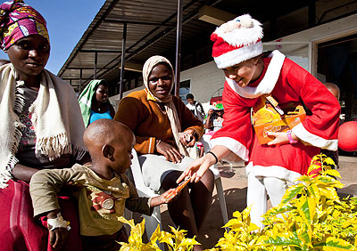 Mother Xmas Anya Johnson (R) gives a gift to a child at the party. The New Times/T. Kisambira.