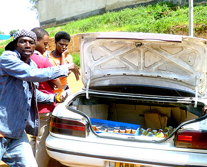 Anaclet Ntakirutimana (R) and a helper(L) sell Nyabisindu yoghurt from a car trunk around T2000 super market in downtown Kigali on December 18. The New Times / JC Tabaro.