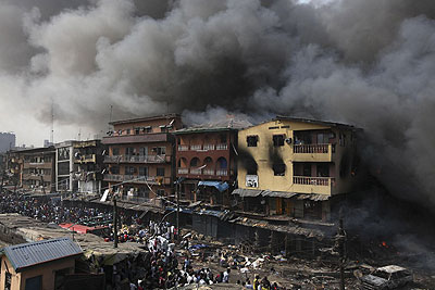 Residents look as a fire burns out residential homes and a warehouse on Lagos Island in Lagos, Nigeria, Wednesday, Dec. 26, 2012. An explosion ripped through a warehouse Wednesday where witnesses say fireworks were stored in Nigeria's largest city, sparking a fire. Net photo