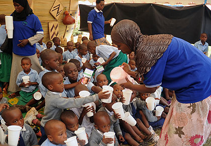 School children being given milk; Last year Rwanda reduced moderate malnutrition by half. The New Times / John Mbanda.