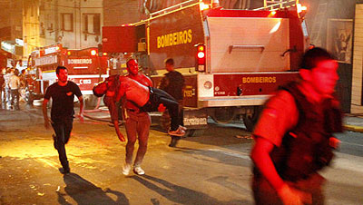 A man carries an injured man, victim of a fire at the Kiss club in Santa Maria, Brazil, early Sunday, Jan. 27, 2013. / Net photo