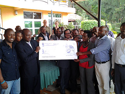 Partners in Health staff hand over a dummy cheque to Hategekima (2ndL). The New Times/ J. Mbanda.