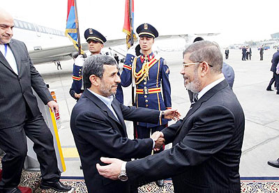 A photo made available by Iranian President Mahmoud Ahmadinejadu2019s official Web site shows Egyptian President Mohamed Morsi, right, greeting Ahmadinejad at the Cairo airport Tuesday. Net photo.