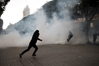 Protesters ran from tear gas during clashes with the police in Tunis on Thursday. New unrest has been set off by the assassination of the politician Chokri Belaid. Net photo.