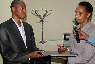 The Director-General for Science and Technology in MINEDUC, Dr Marie Christine Gasingirwa (R), hands over a laptop to WDA Deputy Director-General (Training) Iru00e9nee Nsengiyumva on Thursday. The New Times/ John Mbanda