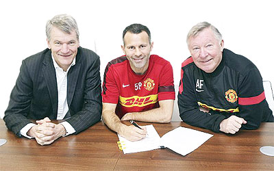 Ryan Giggs puts pen to paper with manager Sir Alex Ferguson (right) and chief executive David Gill.  Net photo.