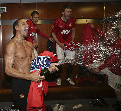 Rio Ferdinand sprays the champagne in the dressing room as Javier Hernandez and Michael Carrick watch on. Net photo.