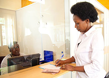 A client banking money at Umurenge Sacco Bank. The New Times/T. Kisambira.