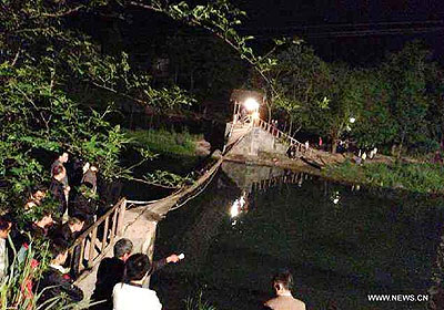 The tilted suspension bridge in Fenghuang County, central Chinau2019s Hunan Province. About 40 people, who returned from a bonfire party, were on the bridge when the bridge floor suddenly tilted in Fenghuang at around 9:10 p.m. on May 1, and more than 20, including children and elderly people, fell into the 1.2-meter-deep river water. Net photo.