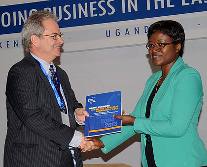 David Bridgman, the manager of Investment Climate Africa Ltd, hands over the Doing Business report to EAC Affairs minister Monique Mukaruliza in Kigali, yesterday. Rwanda is the best EAC country to invest in, the report says. The New Times/ John Mbanda.  