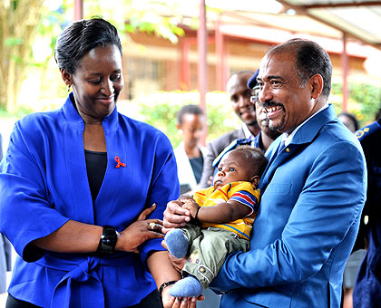 First Lady Jeannette Kagame (L) and UNAIDS envoy Michel Sidibe play with a baby at Kacyiru Health Centre, yesterday,  during their assessment visit to Isange One Stop Centre and the services provided to survivors of Gender-Based Violence and child abuse.    The New Times/ Village Urugwiro.