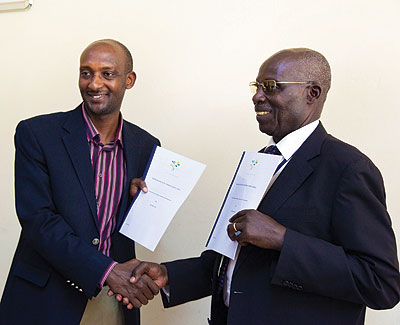 Tusabe (left) and Caesar Nyilidandi, the managing director of Traders Limited exchange documents after the signing of the pilot project agreement last week. The New Times / Timothy Kisambira.