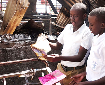 Steven Niyigena (L) is joined by a fellow student as he goes through the burnt remains of his notebooks. The New Times/ JP Bucyensenge.