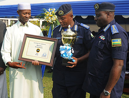 Harelimana (L) awards Western Region Police Commander Seminega as IGP Gasana (R) looks on yesterday. he New Times/ J. Mbanda.