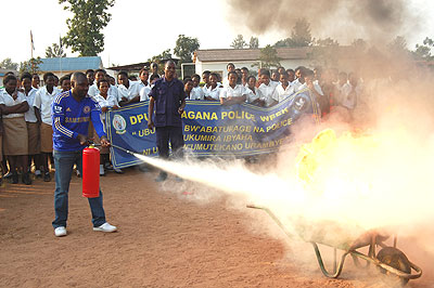 An officer from the Police Fire Brigade watches as a resident demonstrates how to fight fire. The New Times/ S. Rwembeho.