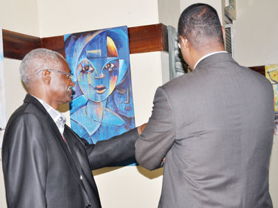 Epa Binamungu (L), the head of Isu00f4ko Arts Rwanda, explains to Minister Protais Mitali, the art pieces displayed at the u201cHello East Africa.u201d