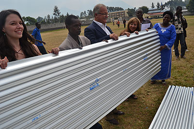 Some of the beneficiaries  with the iron sheets they received yesterday .   The New Times/  Jean du2019Amour Mbonyinshuti