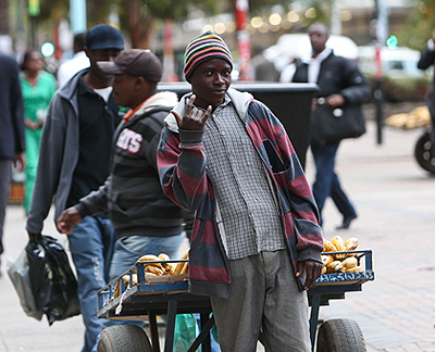  A vendor selling bananas poses in front of his cart in the downtown of Harare. Xinhua