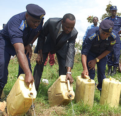 IGP Emmanuel Gasana, Southern Province Governor Alphonse Munyantwari and Deputy Commissioner General of Police Stanley Nsabimana decant crude gin (Kanyanga) into a pit in Nyanza Di....