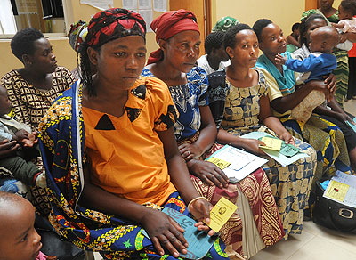 Women await healthcare at a facility while holding their health insurance cards. The New Times/ File.