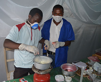 Nshyimyumuremyi (L) and his laboratory attendant  manufacture a product in their mini- laboratory.