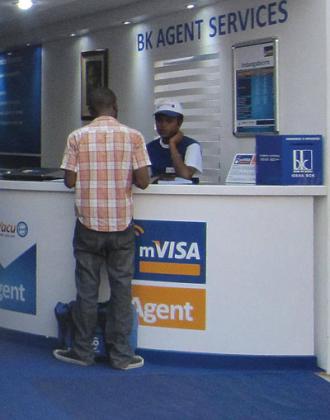 A Bank of Kigali mVisa agent serves a client. Mobile platforms like this ease access to banks services 