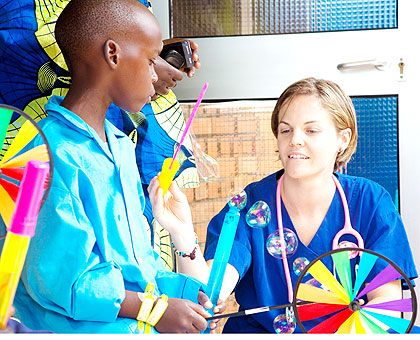 Carly Steeger (R), a nurse, takes  Moses Hirwa through a blowing exercise after the latter underwent a successful heart operation at King Faisal Hospital, Rwanda, yesterday. Volunteers from Open Heart International, Australia, have so far operated on 13 children in the free surgical exercise being done in conjunction with local surgeons.  The New Times/ Timothy Kisambira.