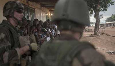 People stand next to French soldiers patrolling to secure an area after exchanges of gunfire during a disarmament operation in the Combattant neighbourhood near the airport of Bangui. Net photo.