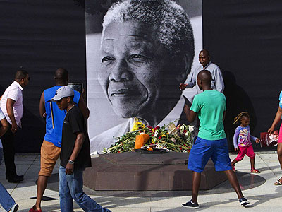 Young people place flowers near a portrait of the late Nelson Mandela in South Africa. Net photo