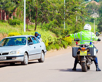 A Traffic Police officer flags down a car for routine inspection in Kicukiro District. The New Times/File