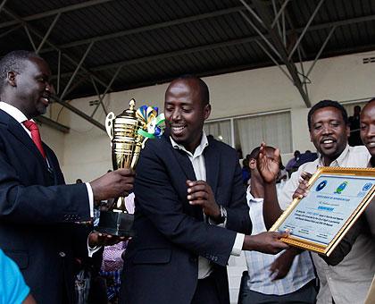 Kimihurura Sector Executive Secretary Mapambano Nyiridandi (C) flanked by other sector staff is awarded with a certificate by the Minister of Natural Resources Stanislas Kamanzi fo....