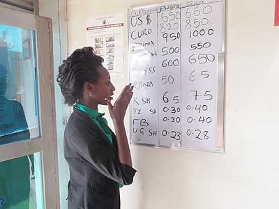 A customer checks forex rates. The local unit had lost 5% value by mid-December. The New Times/ File