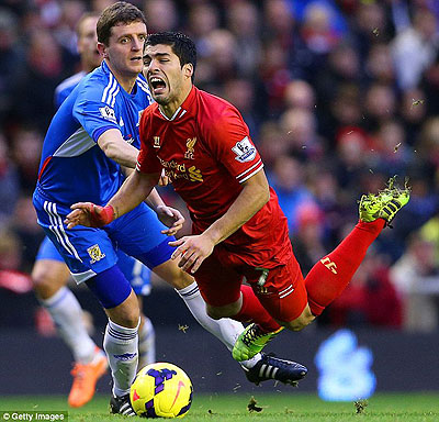 Liverpool striker Luis Suarez goes down under the challenge of Hull City's Alex Bruce at Anfield. Net photo.