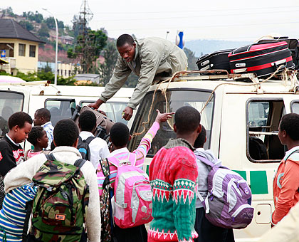 Students drag their heavy bags in the taxi park. Education Times / T. Kisambira