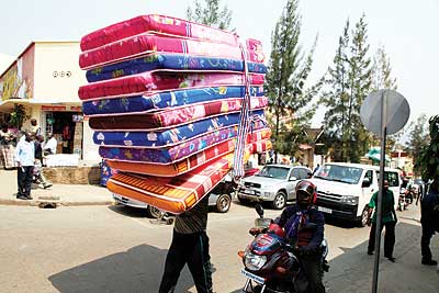 A casual labourer carries mattresses at downtown in Kigali. The New Times/ T.Kisambira.