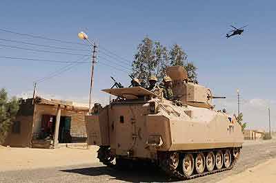 Egyptian Army soldiers patrol in an armored vehicle backed by a helicopter gunship during a sweep through villages in Sheikh Zuweyid, northern Sinai, Egypt. Net photo.