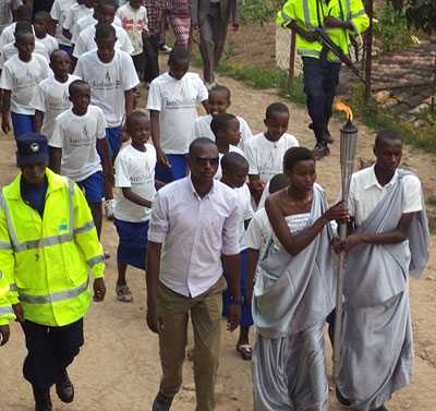 Two 20-year-olds accompaigned by 20 kids carry the Kwibuka Flame from Mukebera Stadium to Rutsiro District headquarters on Sunday. Jean Pierre Bucyensenge