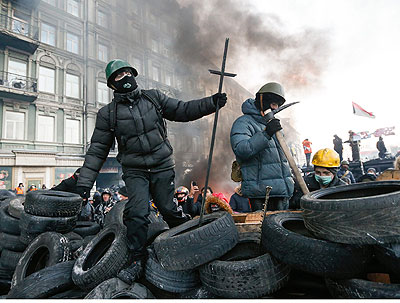 Protesters stand on a barricade during an anti-government protest in downtown Kiev. Net photo.