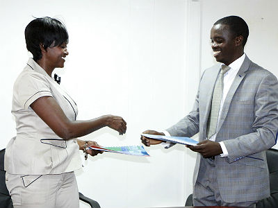 Maria Legodi Busisiwe, Director General, CIMERWA (L), and Pierre Kalinganire, Chief Executive Officer, Peat Energy Company, exchange documents after signing the deal. (Courtesy)