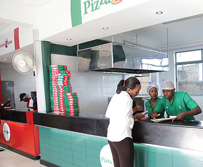 Woodland Pizza Inn workers serve a customer. The firm offers client-centred services at all its businesses.  The New Times / John Mbanda