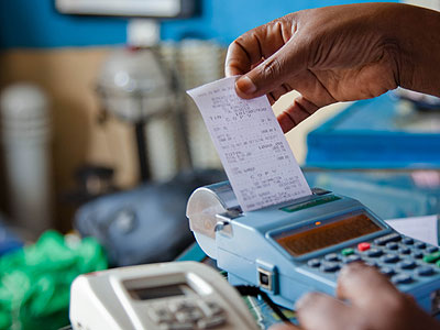 A trader in Quartier Matheus pulling a receipt out of the billing machine. (Timothy Kisambira)