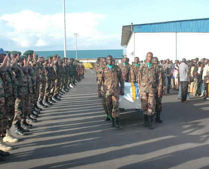 RDF soldiers salute a casket bearing a fallen peacekeeper on arrival at Kigali International Airport last year as family members (R) look on. (File)