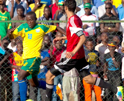 Amavubi striker Michel Ndahinduka skips away from Libya skipper Ahmed Saad Osman during yesterdayu2019s CAN 2015 Qualifier. (Timothy Kisambira)