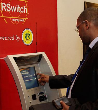 A client withdraws money from an Rswitch ATM. Timothy Kisambira.  