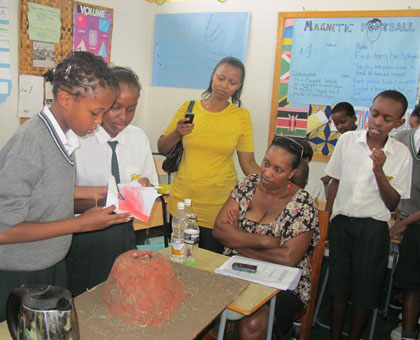 Learners carry out an experiment as their parents watch. The new curriculum will help in dealing with the habit of cramming. (Timothy Kisambira)