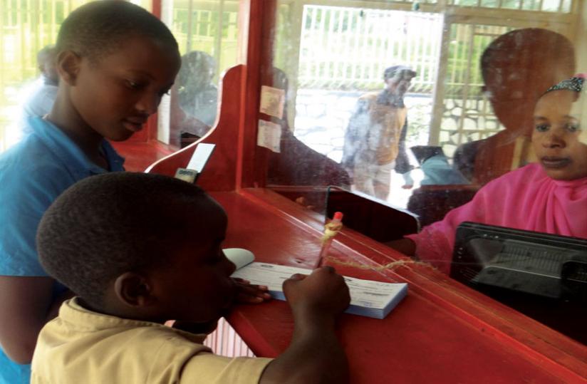 Children fill forms to deposit money. Microfinance sector players have joined efforts geared at encouraging children to save. (P. Tumwebaze)