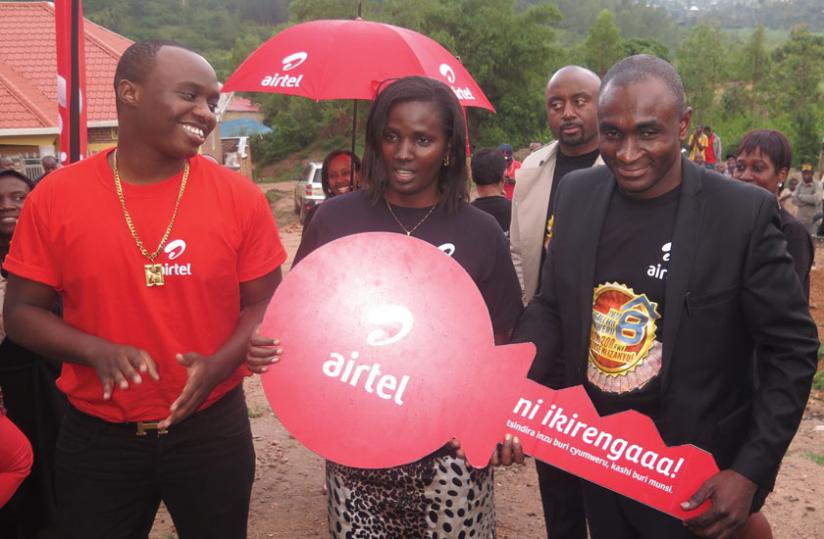 Mbabazi receives a dummy key to her house from Airtel finance director Tano Oware as local singer and Airtel brand ambassador, King James cheers. (Thu00c3u00a9ogu00c3u00a8ne Nsengimana)