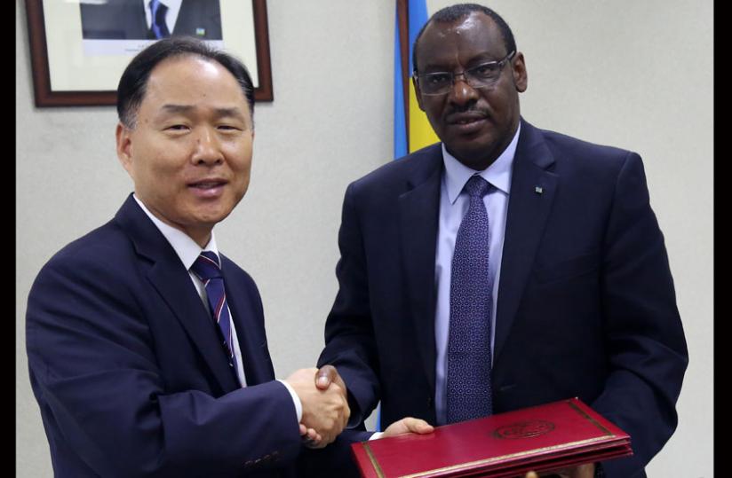 Korean Ambassador to Rwanda Soontaik Hwang and Finance minister Gatete exchange documents after the signing ceremony yesterday. (John Mbanda)