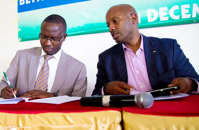 Majyalibu (L) signs paperwork as Amb. Kayonga looks on yesterday. (Timothy Kisambira)